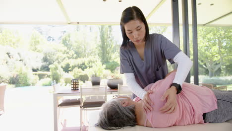 providing physical therapy, caregiver assisting senior woman with exercises at home
