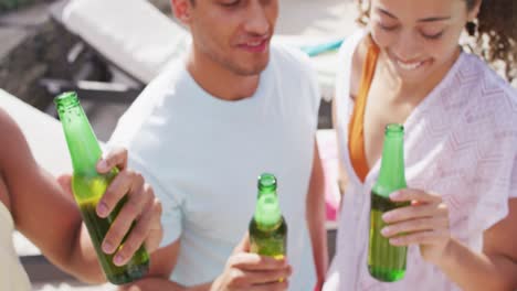 Fröhliche-Gruppe-Verschiedener-Weiblicher-Und-Männlicher-Freunde,-Die-Auf-Einer-Poolparty-Mit-Flaschen-Bier-Anstoßen