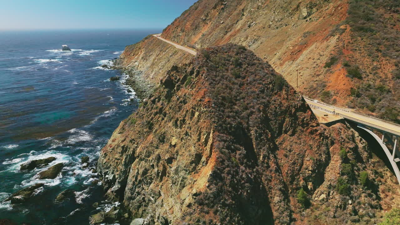 Craggy rugged coastline of California. Dark blue Pacific Ocean with algae accumulation on surface. Top view.