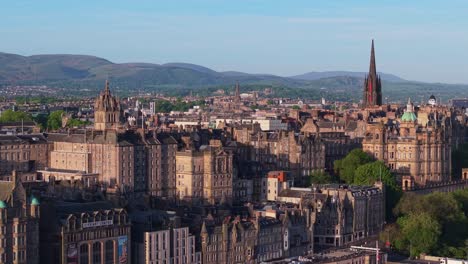 drone glides parallel to the historic buildings of edinburgh's old town, gradually revealing the striking spire of the hub