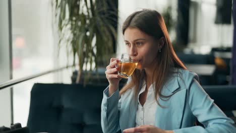 beautiful smiling girl drinking tea and smiling looking out the window