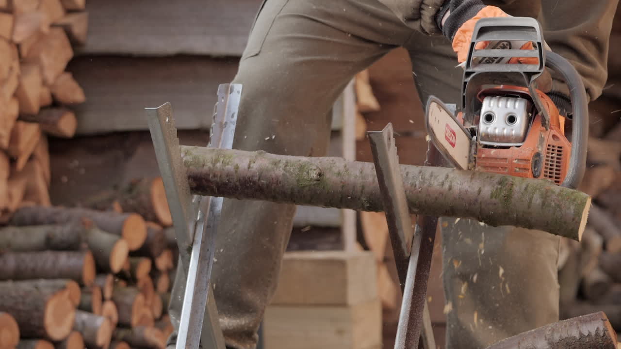 Sawyer man chainsawing wood log with chainsaw in slow motion