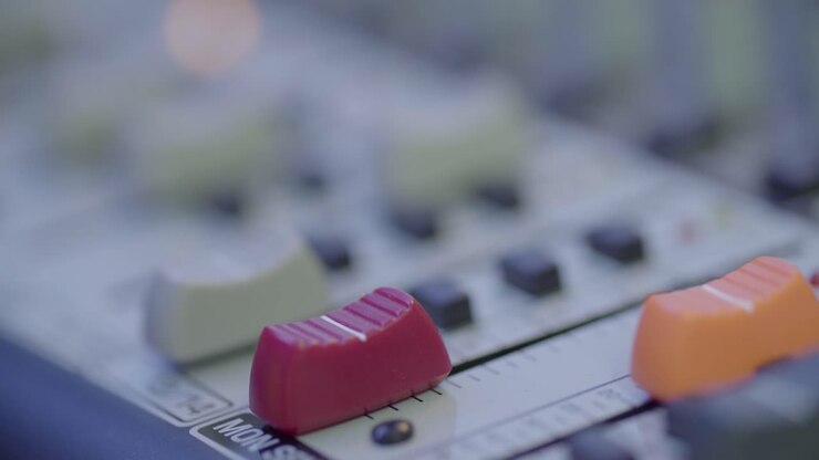 A music producer slides the volume up on the mixer and presses a button
