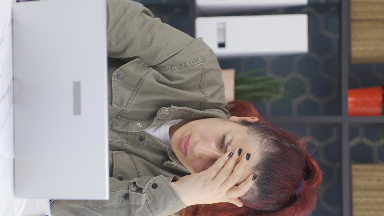 사업가 여성의 수직 비디오는 노트북에서 그의 실패를 슬프게 보고 있습니다.