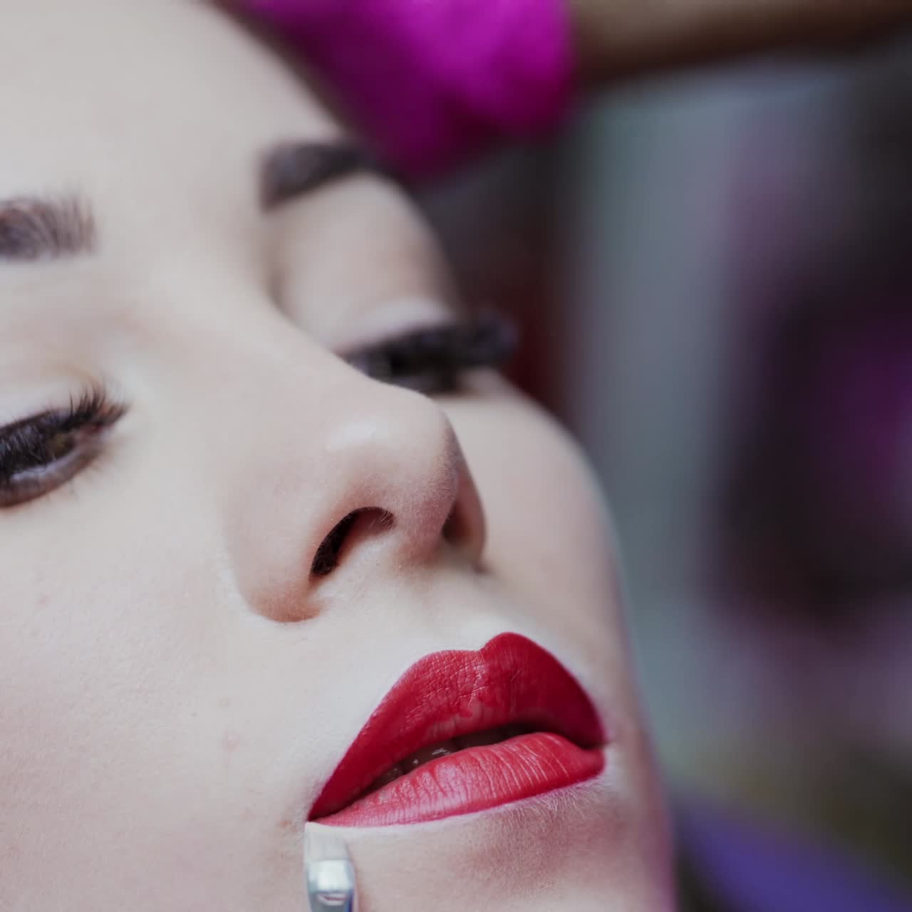 Beautiful face of a woman with perfect make-up. Cosmetic procedure of lips tattooing. Beautician doing permanent makeup on lips.