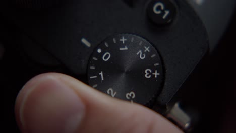 Turning-exposure-dial-on-digital-camera,-close-up-top-down-view