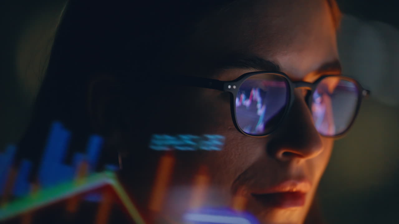 Night worker trades forex at home closeup. Computer charts reflected in glasses