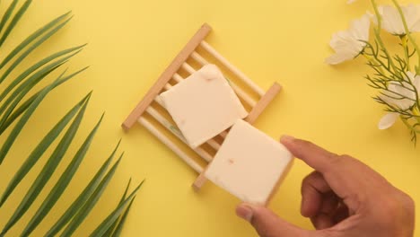 la mano sosteniendo barras de jabón en un plato de jabón de madera