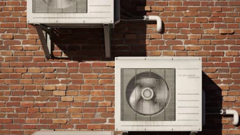 multiple old, rusty outdoor air conditioner units on the brick wall. camera moves upwards in endless, seamless loop. many units providing fresh, cool air to the citizens. city overheat as a result.