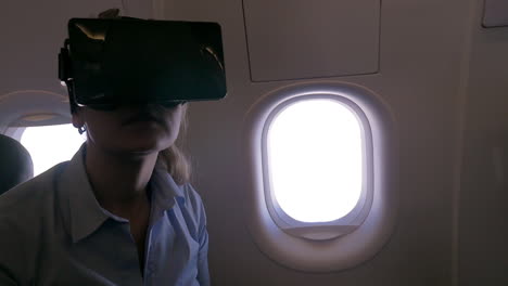 vista en cámara lenta de una mujer usando un casco vr para teléfono inteligente en un avión