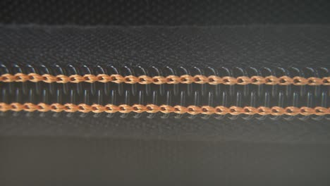 a macro close-up shot of a hard case zipper being opened slowly, orange yellow strings, metal zip, black box, photography gear, professional studio lighting, static 4k video