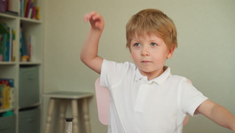 calm blond boy sits at desk listening teacher attentively