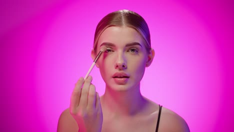 nordic young blonde woman puts skin dusting powder in makeup close up studio shot