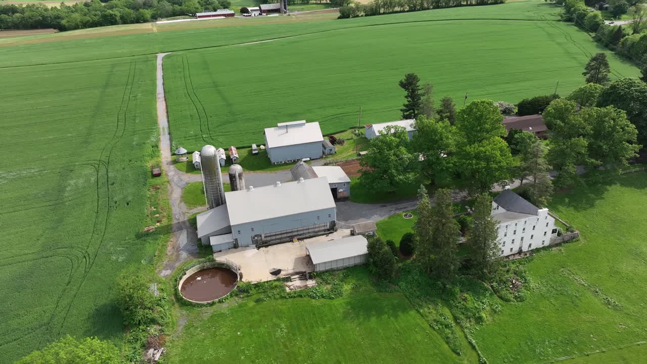 Aerial top down shot of American farmstead with house, silo storage, garden and large agricultural cropland fields. Sunny day in summer season. Pennsylvania, USA.