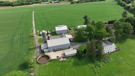 aerial top down shot of american farmstead with house, silo storage, garden and large agricultural cropland fields. sunny day in summer season. pennsylvania, usa.