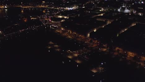 Aerial,-tracking,-drone-shot,-panning-over-the-Kruununhaka-harbor,-overlooking-traffic-at-the-Helsinki-north-harbor,-the-city-full-of-lights,-on-a-clear-summer-night,-in-Uusimaa,-Finland