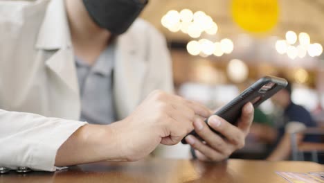 a young businessman wearing a surgical mask is taking a video conference with customers via a smart phone connected to the internet.