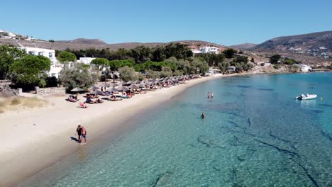 aerial over krios beach seashore with bathers on turquoise waters, paros
