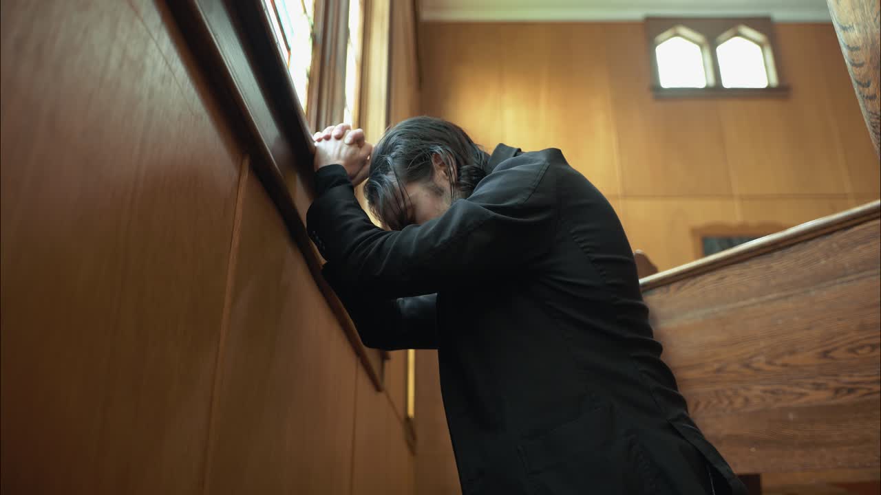 A Christian man, priest, preacher, pastor praying on his knees inside an old church