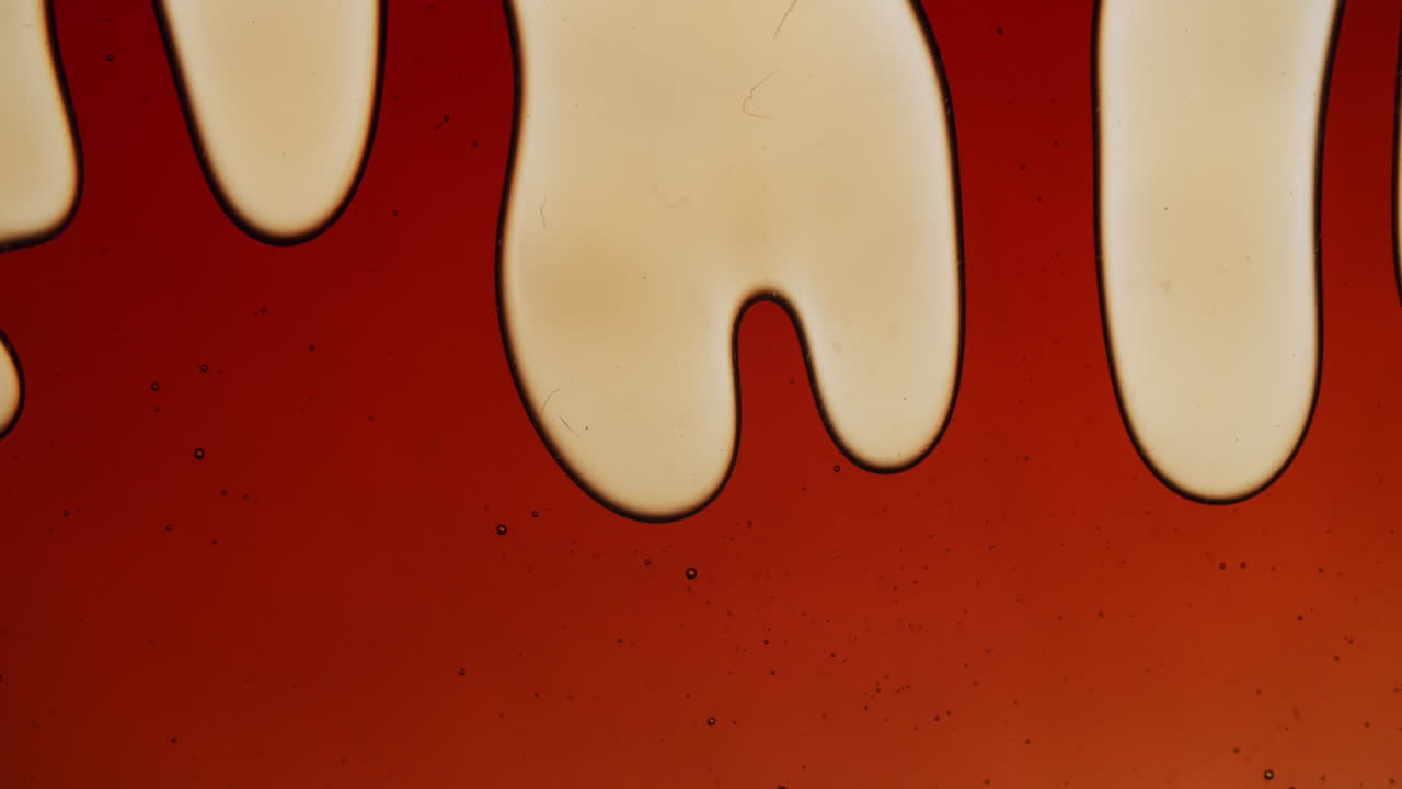 tiro macro de um líquido âmbar escuro se dissolvendo em veias menores e se espalhando novamente