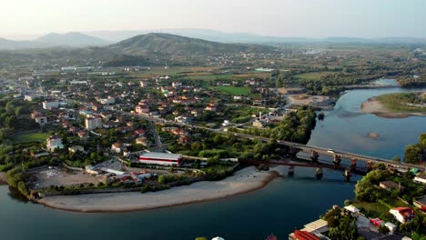 aerial of the city of shkoder in albania with a river, bridge and mountians