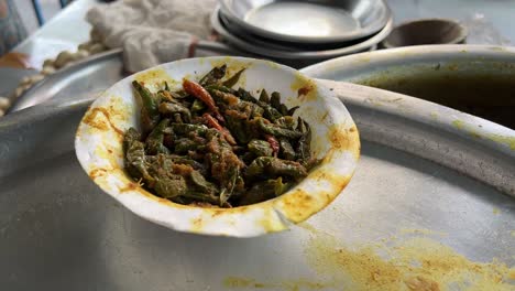 close up shot of sautéed green beans in a paper cup at a roadside food stall in india