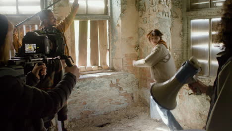 production team and cameraman recording the scene of a girl trying to escape through the window of a ruined building 1