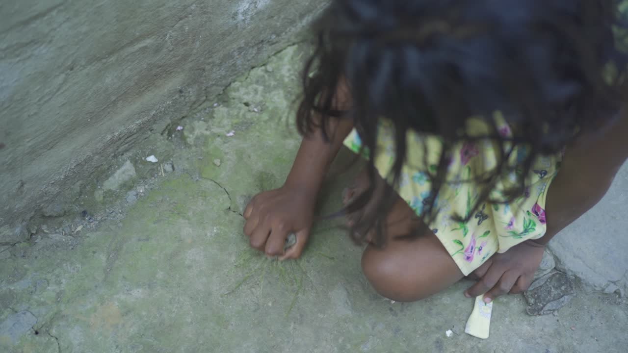 시골 마을에서 돌을 가지고 노는 젊은 인도의 가난한 고아 소녀