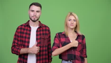 young couple giving thumbs up together