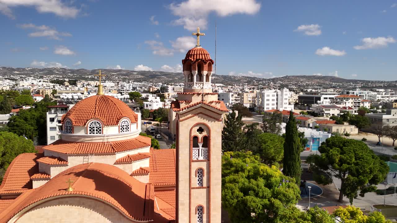 A beautiful perspective of a church tower in Pathos, Cyprus, showcasing the vibrant town below. The bright sky enhances the charm of the surrounding area