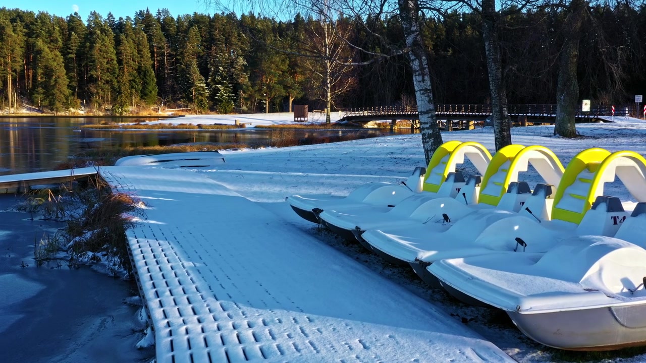 Zamrzlé jezero s molem a sněhem pokrytými šlapadly čekajícími na příchod jara.