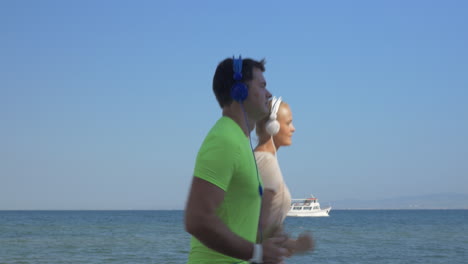 shot of young woman and man in headset are jogging on sea skyline background piraeus greece