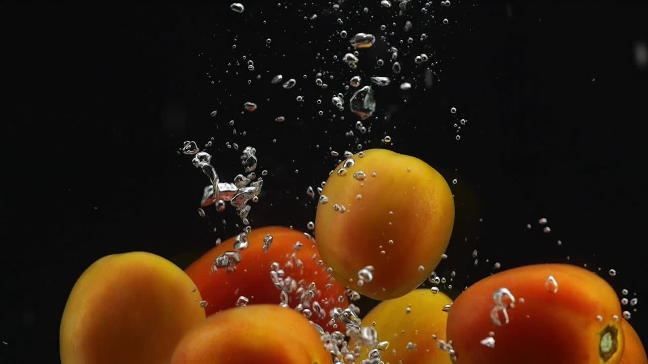 많은 토마토가 검은 바탕에 물에 떨어집니다.