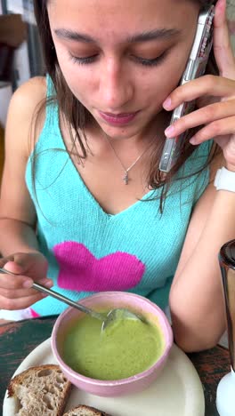 woman eating soup and talking on phone