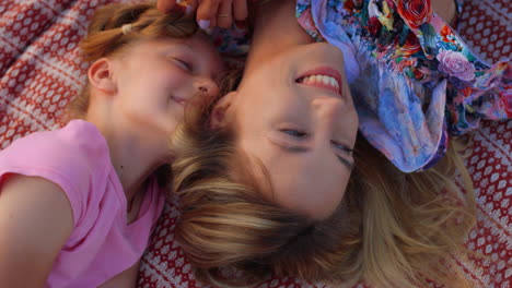 smiling family having fun at meadow. woman playing with girl hair outdoor.