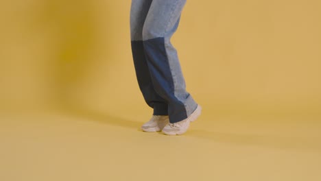 close up on legs and feet of woman having fun dancing against yellow studio background 1