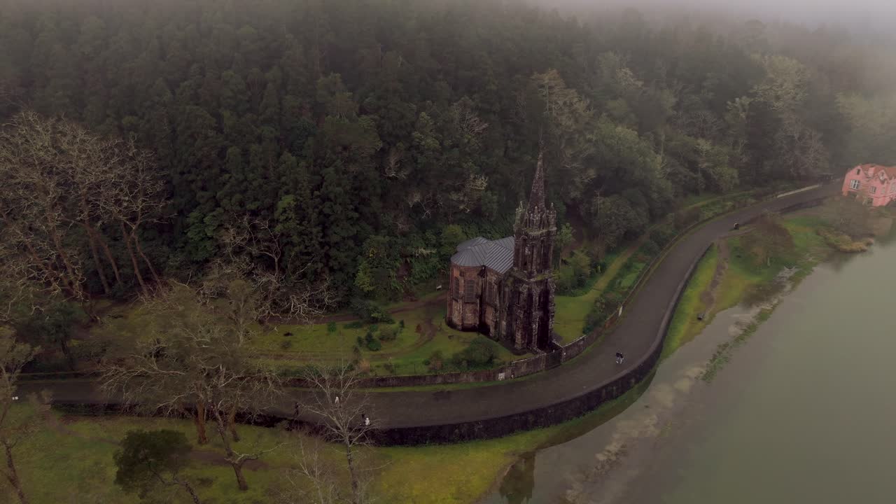 Veduta aerea della cappella di Nossa Senhora das Vitórias accanto al lago Furnas, circondata dalla foresta a São Miguel, Azzorre.