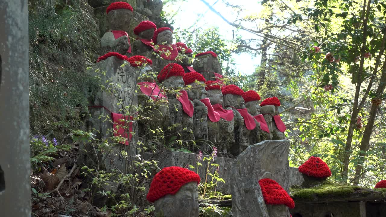 vista bloqueada de las típicas estatuas jizo sintoístas japonesas con sombreros rojos en el bosque