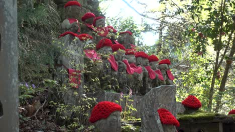 Locked-off-view-of-typical-Japanese-Shinto-Jizo-statues-with-red-hats-in-forest