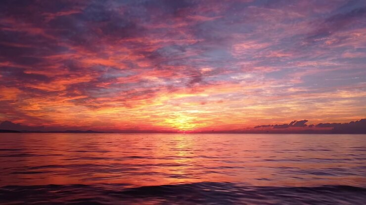 A Stunning Sunset Over Tranquil Waters: Vibrant Hues of Orange, Pink, and Purple Reflecting Off The Serene Ocean Surface Capturing The Beauty of Nature