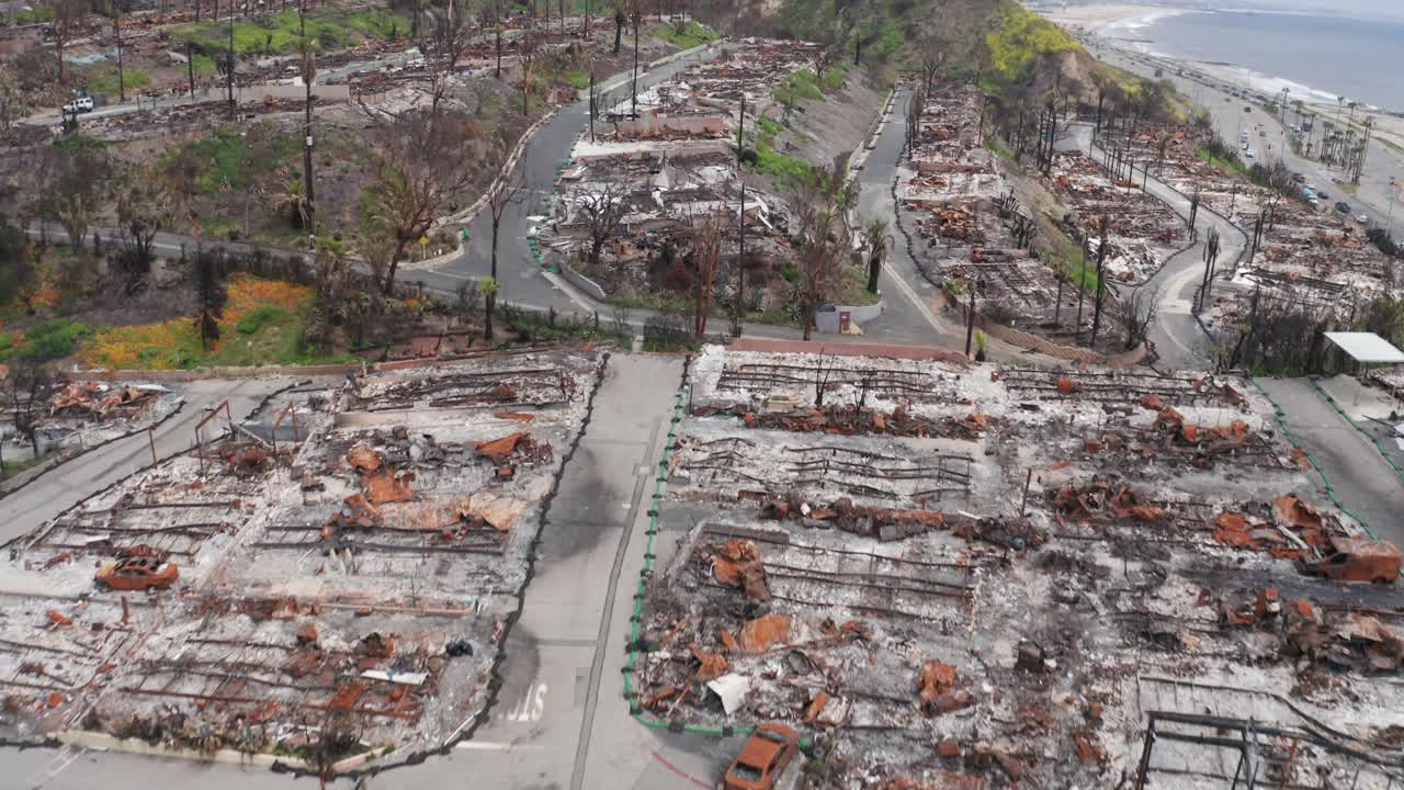 Bird's eye aerial shot flying over an oceanfront gated community destroyed by the Palisades Fire in Pacific Palisades, California. 4K