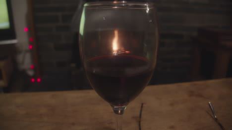 Relajarse-Con-Una-Copa-De-Vino-Tinto-En-Una-Acogedora-Habitación-Junto-Al-Fuego-Viendo-La-Televisión,-Paralaje