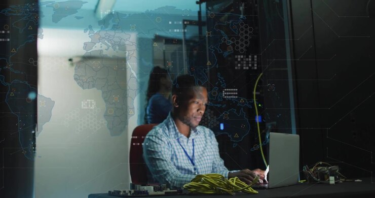 IT technician typing laptop in server room, initiating animated network map overlays for monitoring