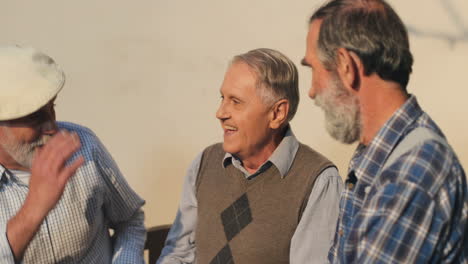 Senior-Retired-Man-In-A-Cap-Joining-His-Friends-Neighbors-On-A-Bench-And-Shaking-Them-Hands