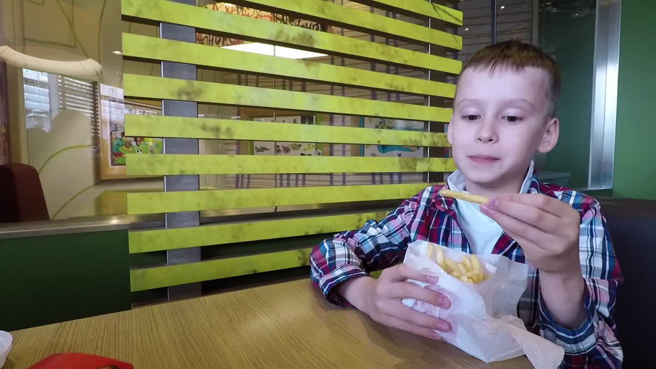 Ragazzo che mangia fast food. Ragazzo felice che mangia patatine fritte al ristorante