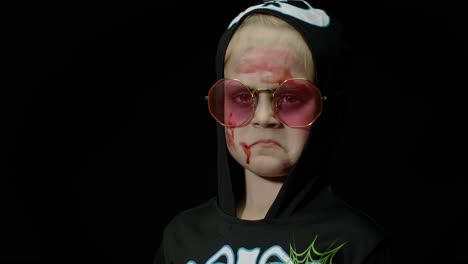 halloween, angry girl with blood makeup on face. kid dressed as scary skeleton, posing, making faces