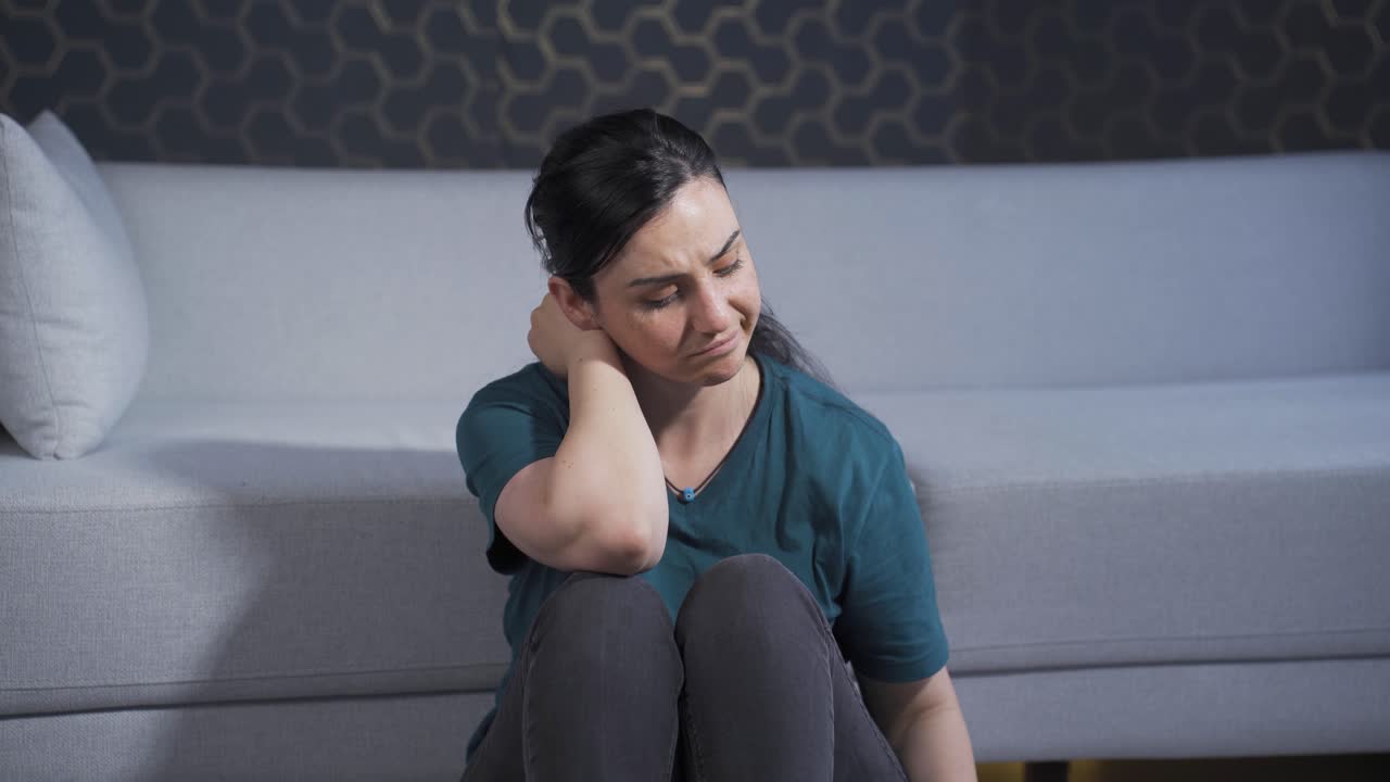 una mujer exhausta y reflexiva apoyando la cabeza contra la pared.