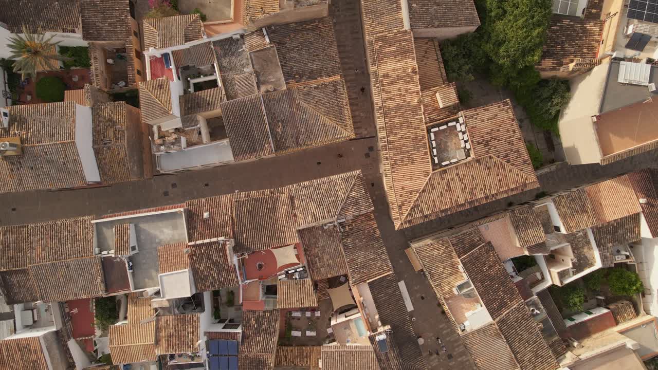 Top-down aerial footage of a Mediterranean town with traditional terracotta rooftops. The video captures a warm, rustic charm with small courtyards, rooftop terraces, and a compact urban layout.