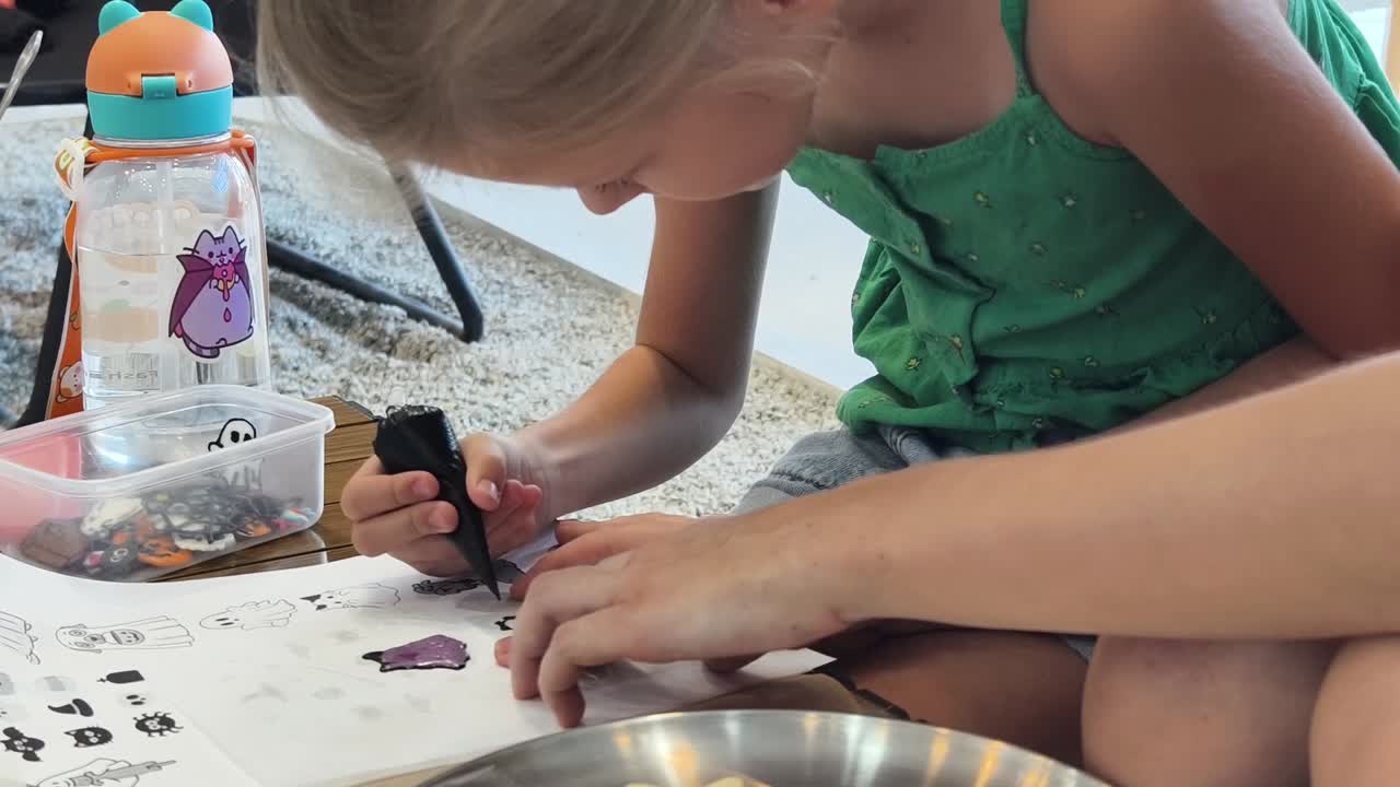 Bambino che decora biscotti di Halloween sotto la supervisione di un adulto