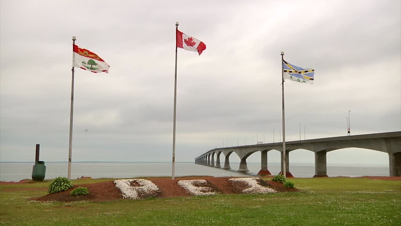 A wide shot of 3 flags with PEI written in the red earth below